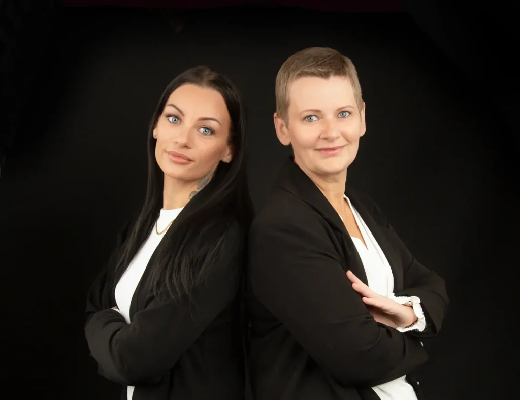 Billede af Katja og Mie som er bag klinik kiergaard, de står ryg mod ryg og kigger mod kameraet